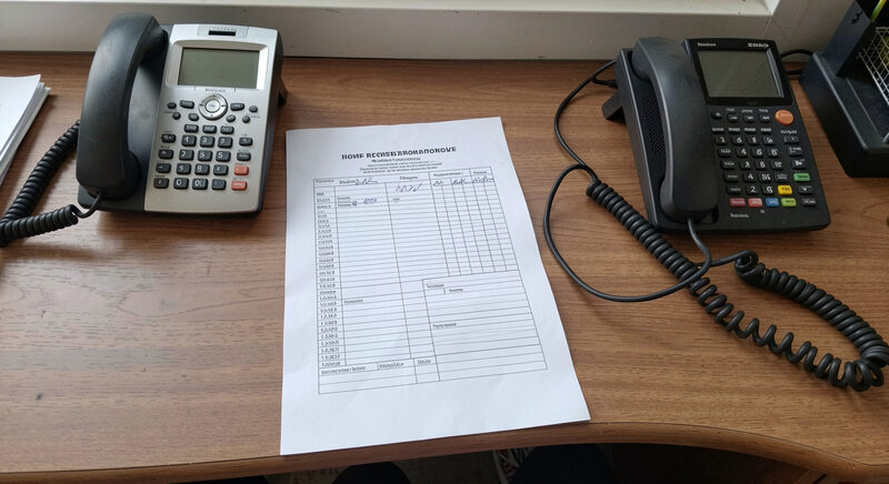 A paper registration form on a desk beside a telephone and an external modem with a coiled cable.