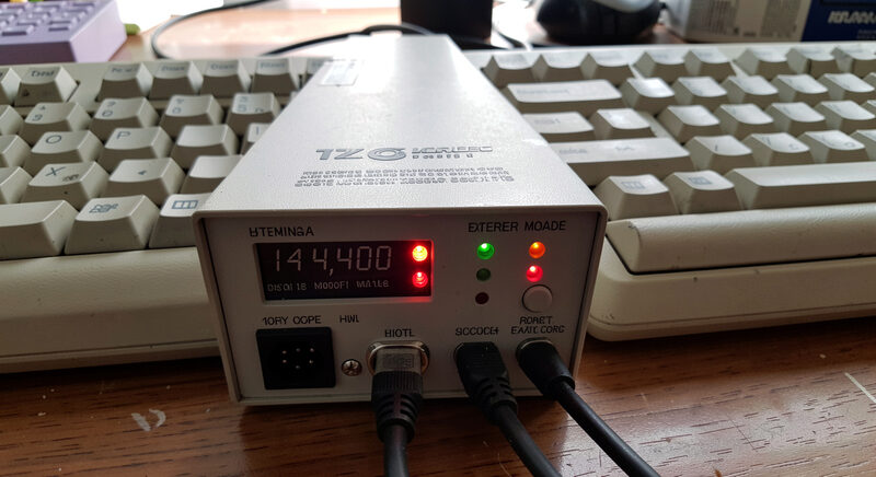 Close-up of a 14,400 baud external modem with glowing status LEDs beside a beige keyboard on a wood desk.